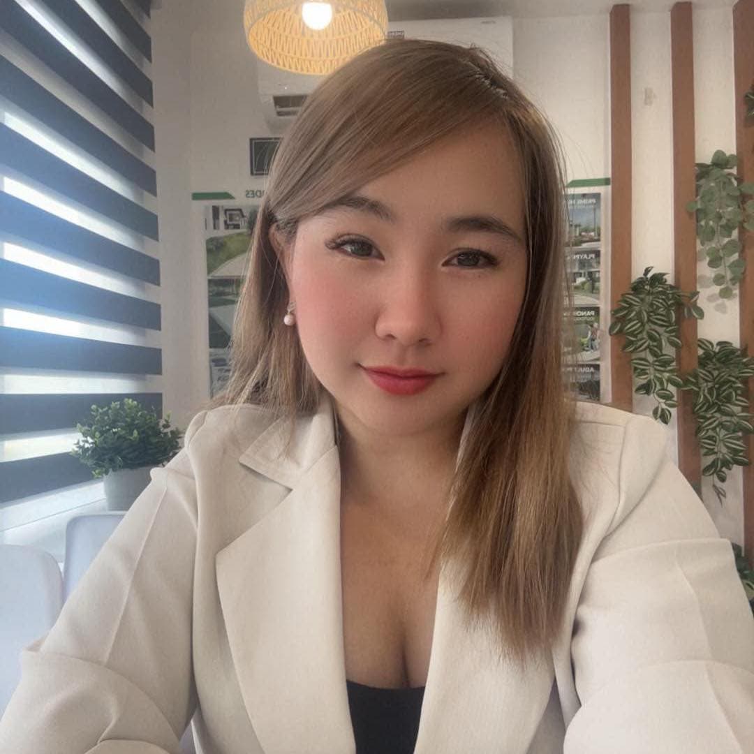 Woman with light brown hair wearing a white blazer, sitting in a bright office.